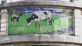 833670 Afbeelding van een van de drie tegelplateaus, voorstellende koeien in de wei, op de winkelpui van de biologische ...